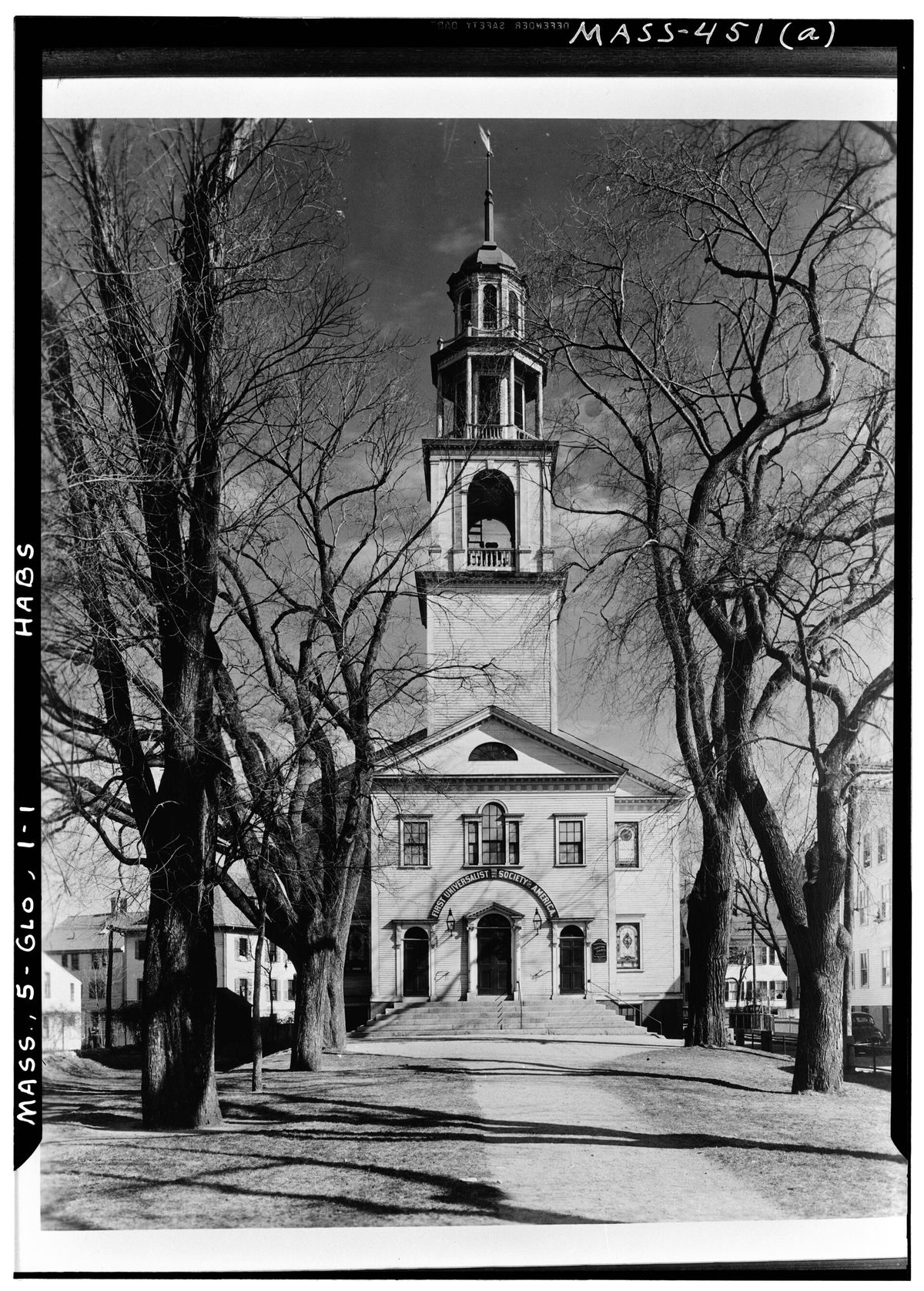 The Universalist meetinghouse on Middle Street in Gloucester and its steeple, framed by bare trees in 1939