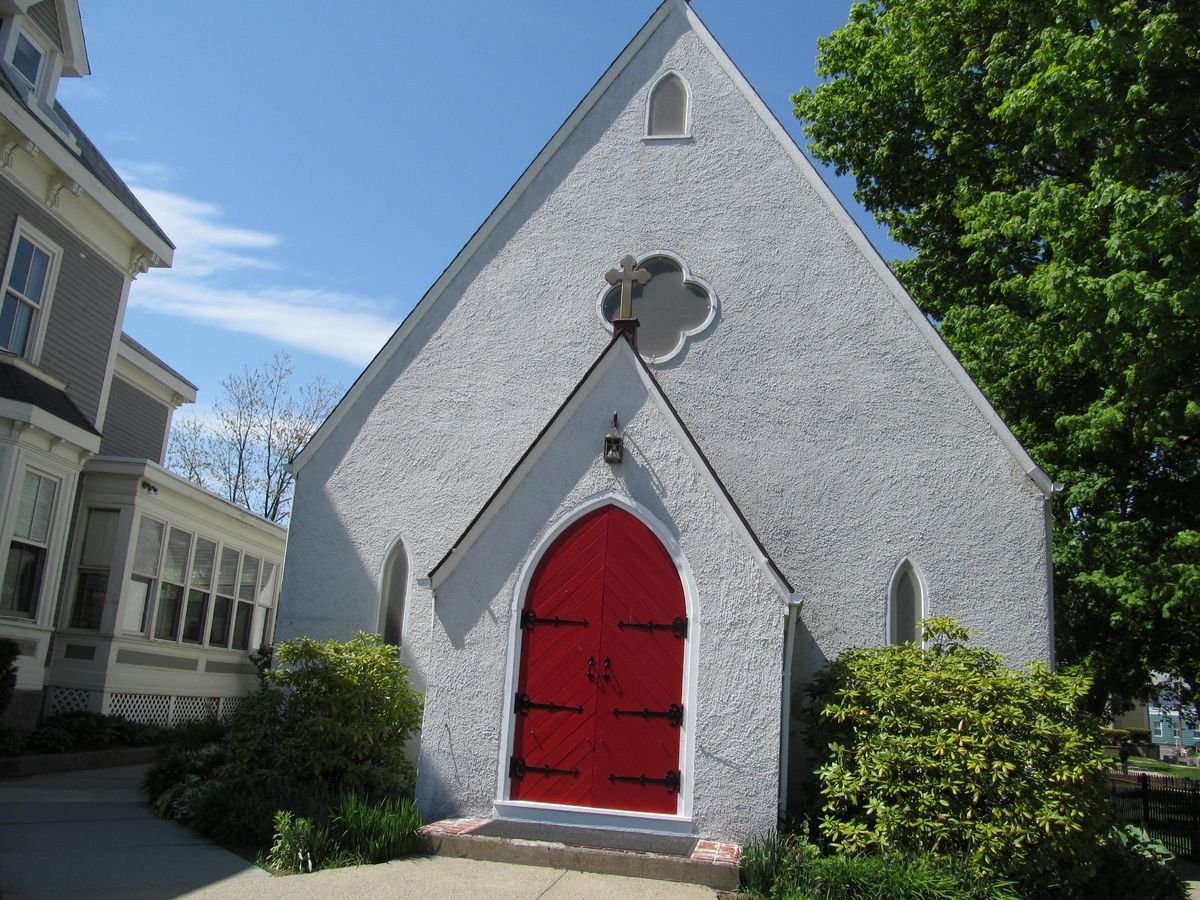 The gray stone gable of St. John's Episcopal Church on Middle Street with its red front door