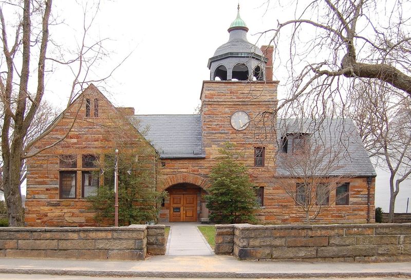 The Manchester-by-the-Sea Public Library, a stone building with arched windows and a tower, on Union Street