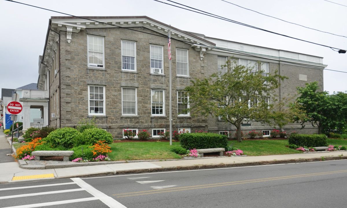 The Rockport Public Library, a long granite building with rows of windows, on School Street in Rockport